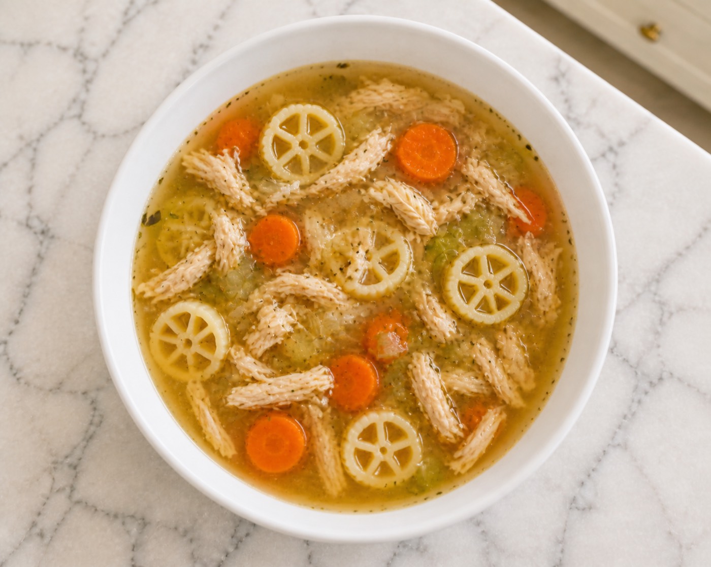 Wagon Wheel Chicken Soup, photographed on white marble in the A More Perfect Supper kitchen